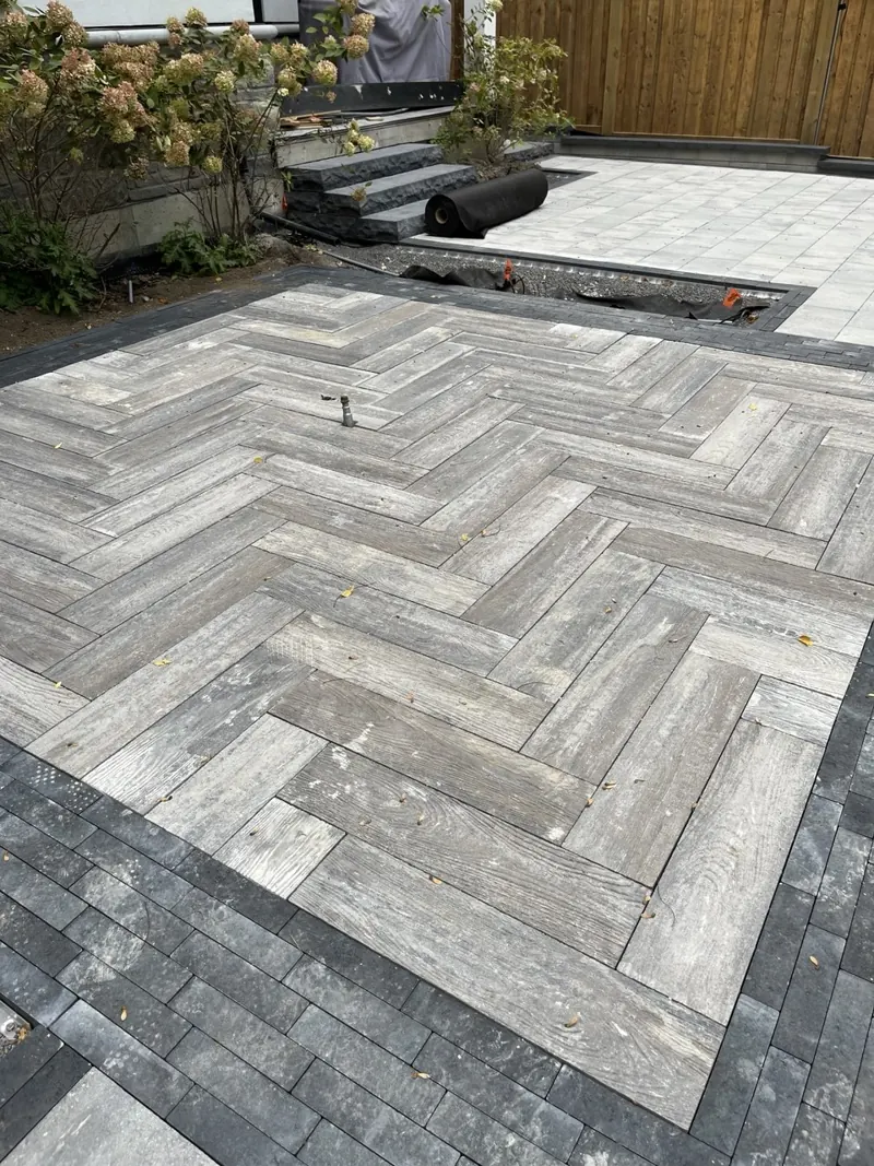 Backyard herringbone pavers framed by a charcoal border