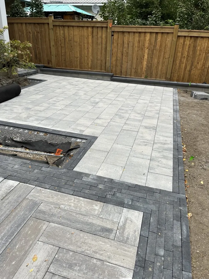Backyard interlock with a wide contrast border beside a cedar fence