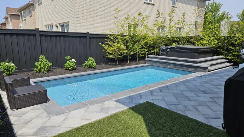 Compact pool with grey pavers, raised spa wall and new planting