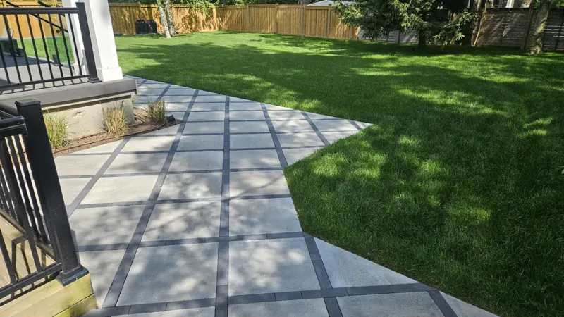 Large slab paver path with charcoal joints curving into a green lawn